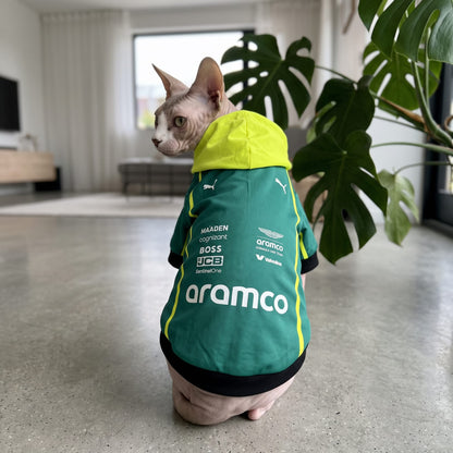 Sphynx cat wearing Aston Martin 2025 pet hoodie back view with yellow hood and aramco logo indoors